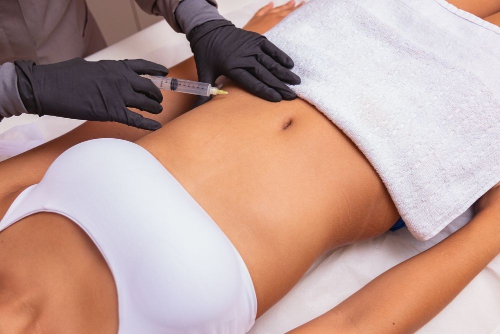 Person receiving an abdominal injection with a syringe.