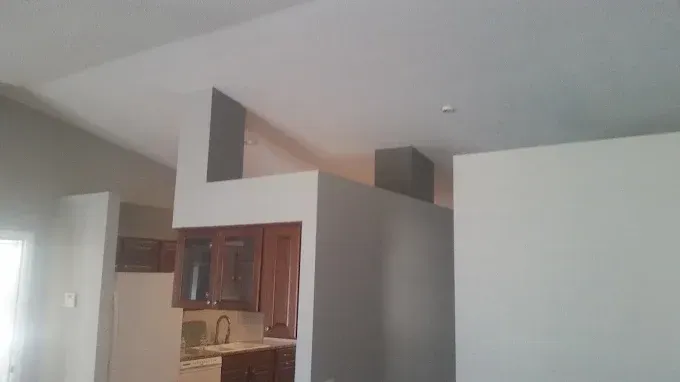 Interior view of kitchen with gray walls and cabinets, white ceiling, and open doorway.