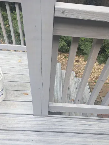 Gray painted deck with steps, railings, and a vertical post.