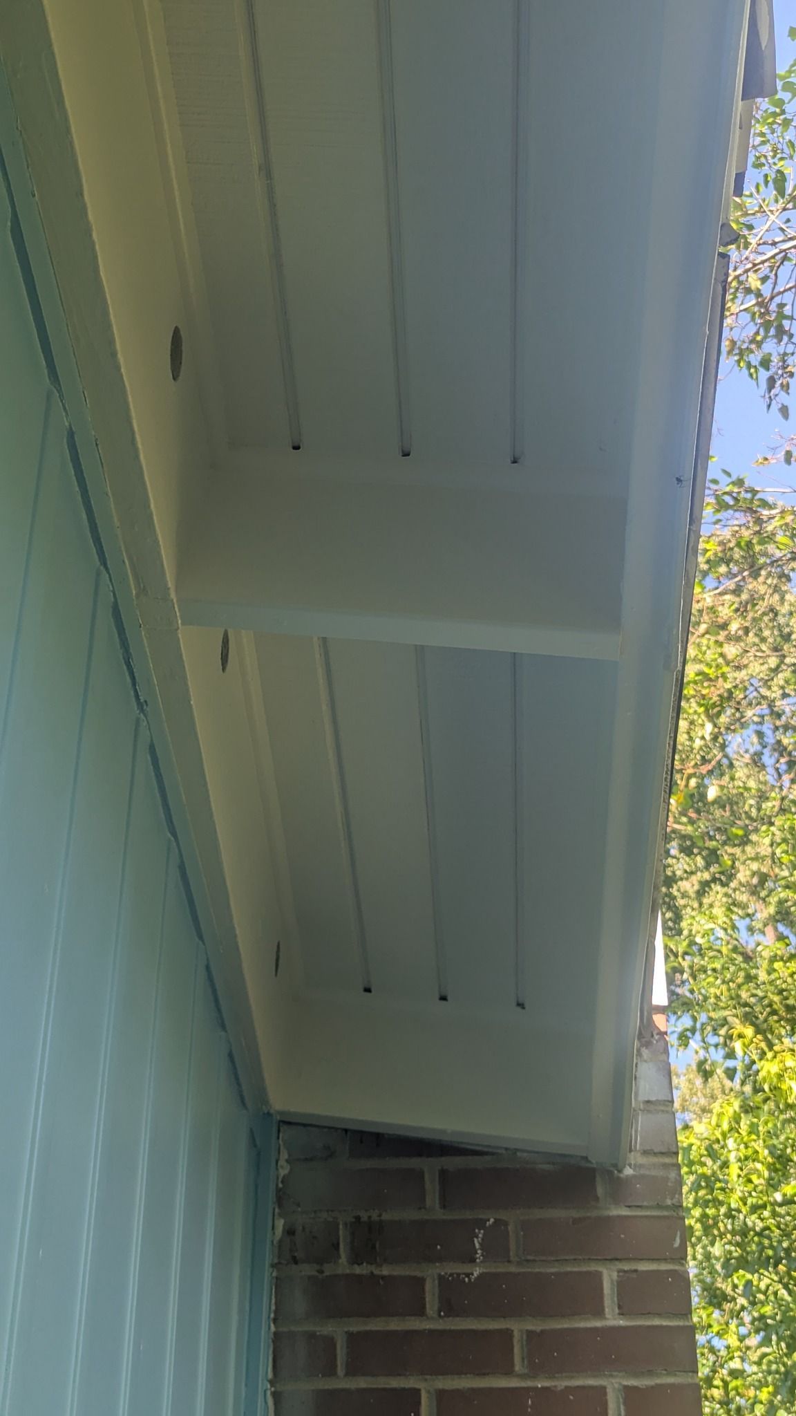 White soffit and support beam over brick and siding.