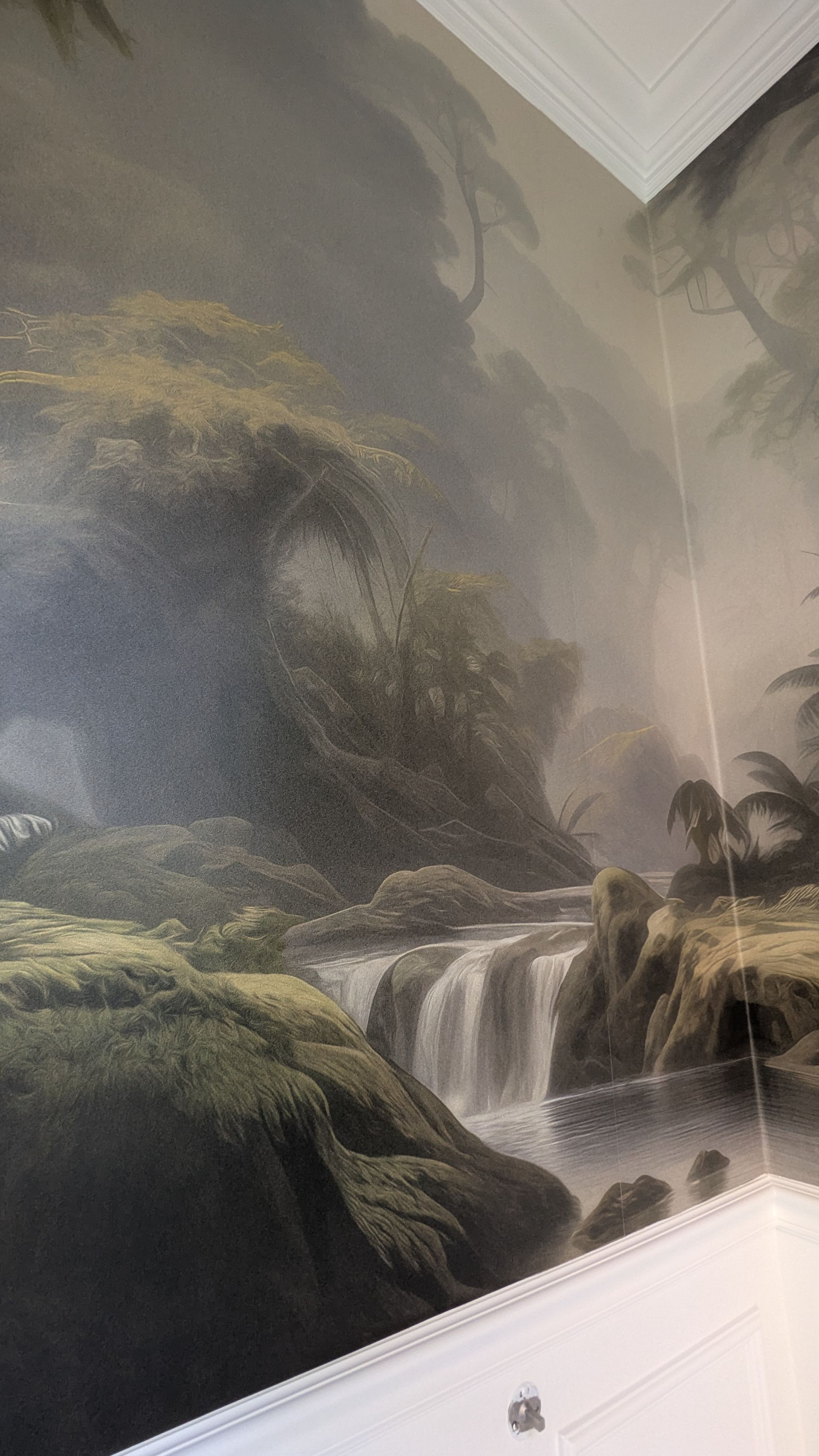 Mural of a misty landscape with a waterfall cascading over mossy rocks and lush foliage.