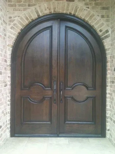 Double wooden front doors with arched top, framed in brick.