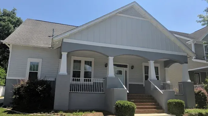 Two-story house with light blue siding and gray trim, porch with columns and steps leading up to the front door.