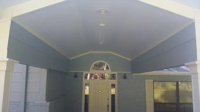 Blue-painted porch ceiling with white trim, a front door, and support columns.