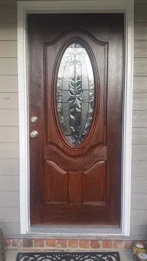 Brown front door with oval glass panel and white trim.