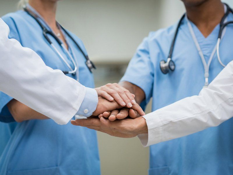 Doctors and Staff Stacking Hands Together — Omaha, NE — Arbor Heights Family Medicine