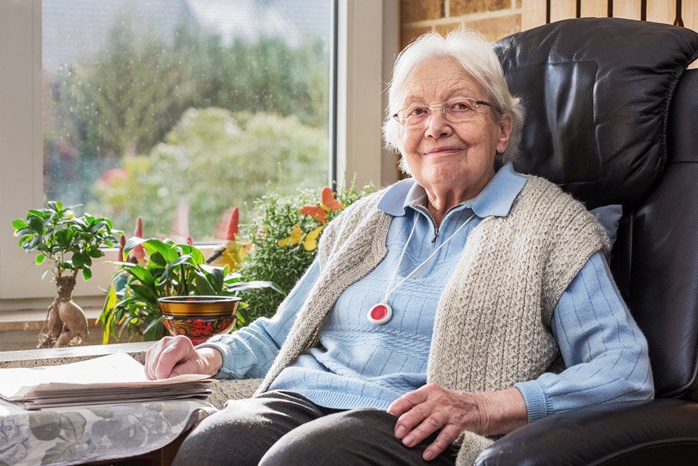 Elderly Person With Emergency Button Sitting On Chair — Country to Coast Cabling in Rockhampton, QLD