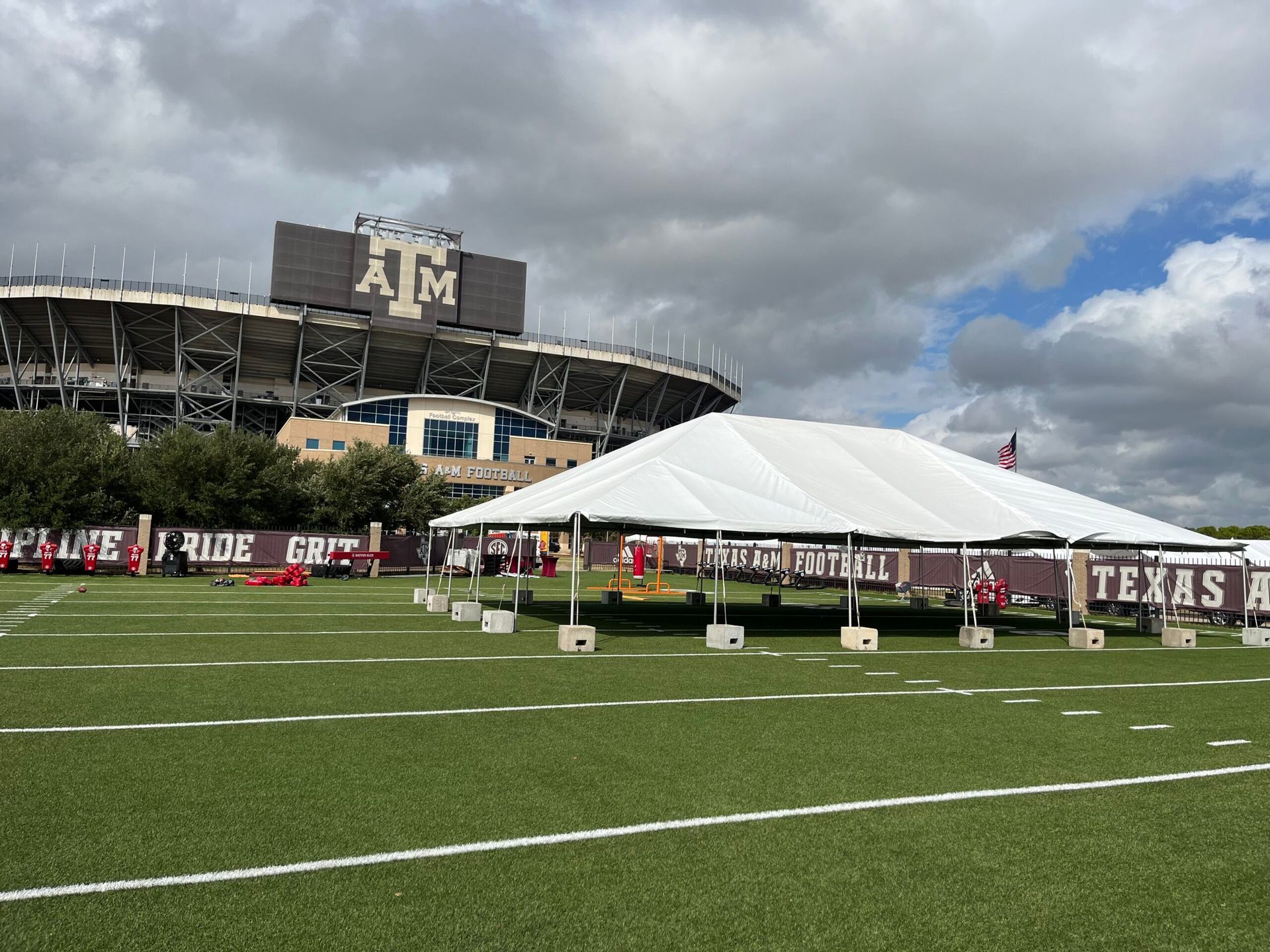A tent set up on a football field in front of a large stadium with 