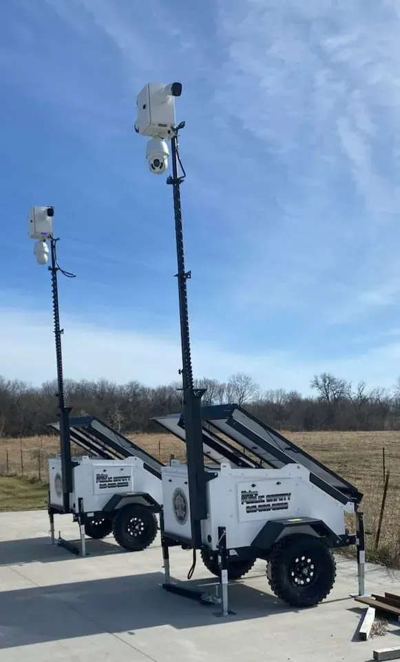 Two trailers with cameras on them are parked next to each other.