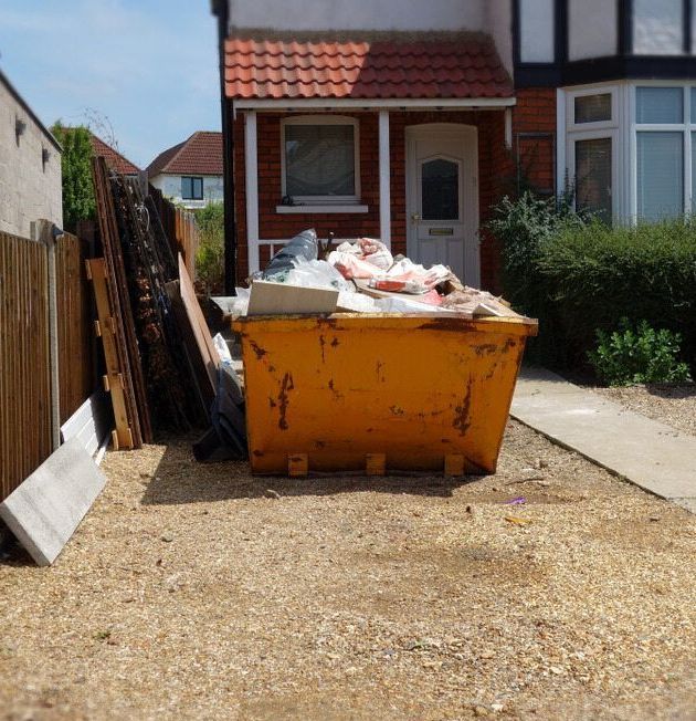 A Green Bag Is Sitting On Top Of A Lush Green Lawn Next To A Pile Of Leaves — Eco Skips In Proserpine, QLD