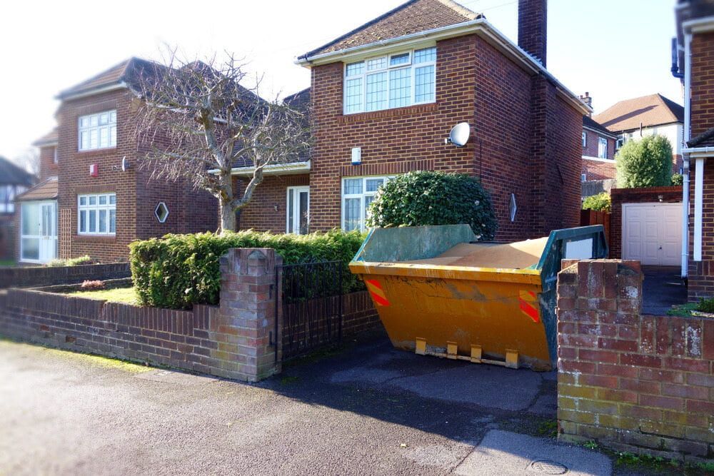 A Large Yellow Dumpster Is Parked In Front Of A Brick House — Eco Skips In Midge Point, QLD