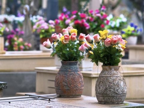 Due vasi pieni di fiori sono appoggiati su un tavolo in un cimitero.