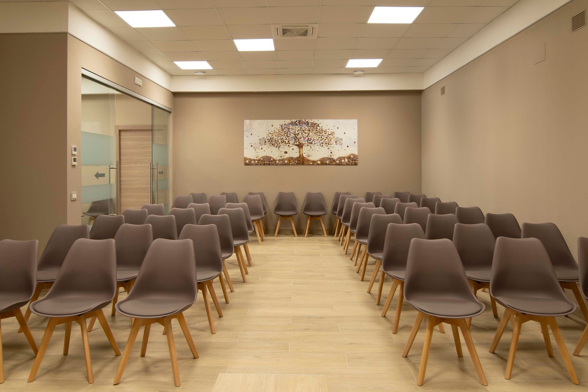 Una stanza con una fila di sedie e un dipinto sul muro.