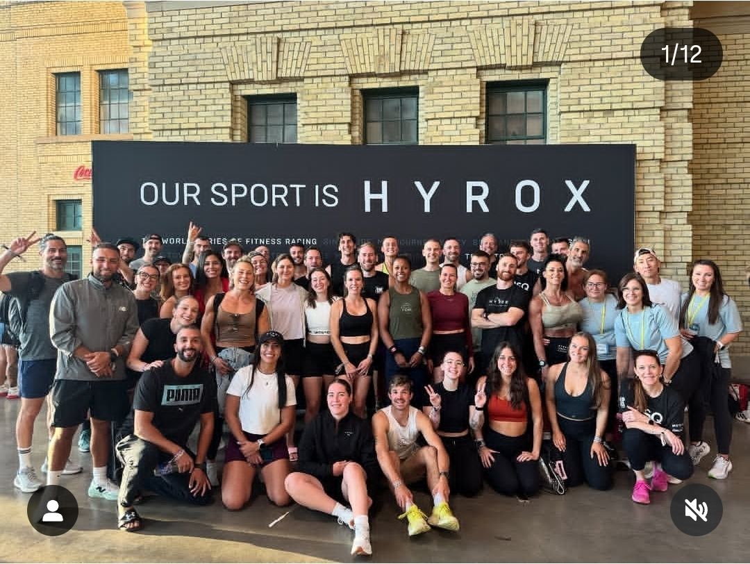 Groupe d'athlètes devant un panneau « NOTRE SPORT EST HYROX » ; fond en brique ; tenues diverses.