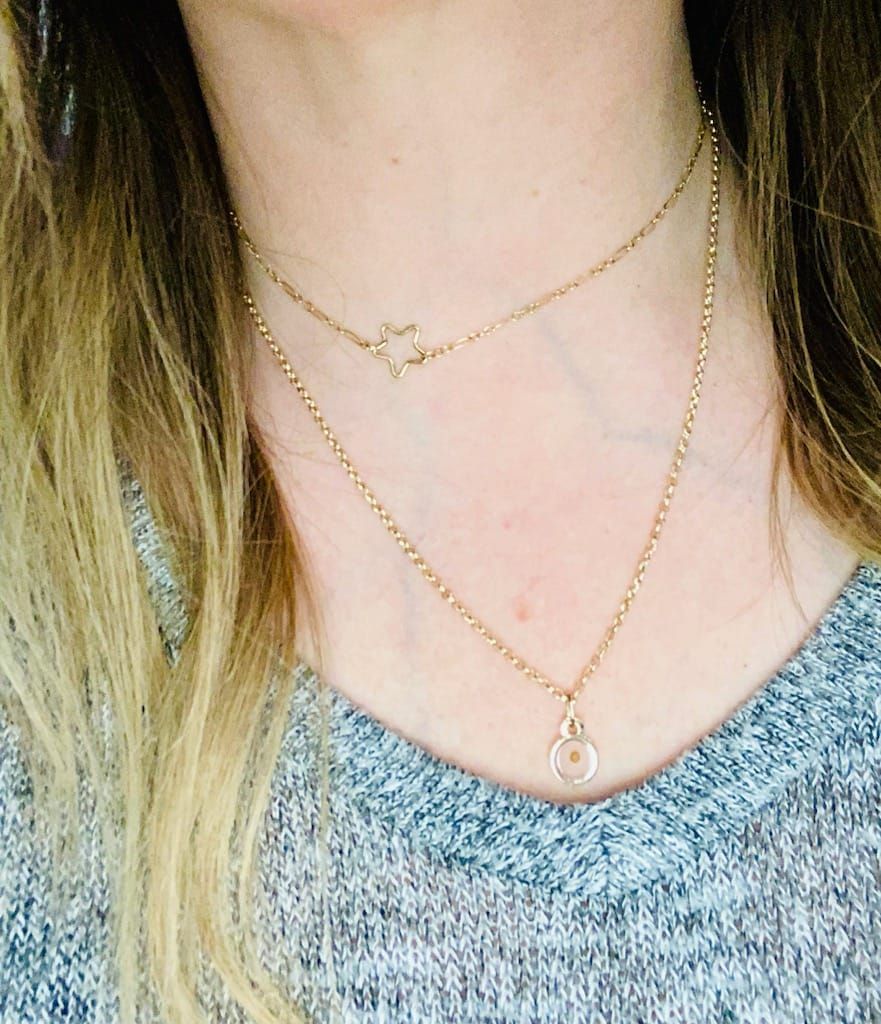 A woman is wearing two necklaces on her neck.