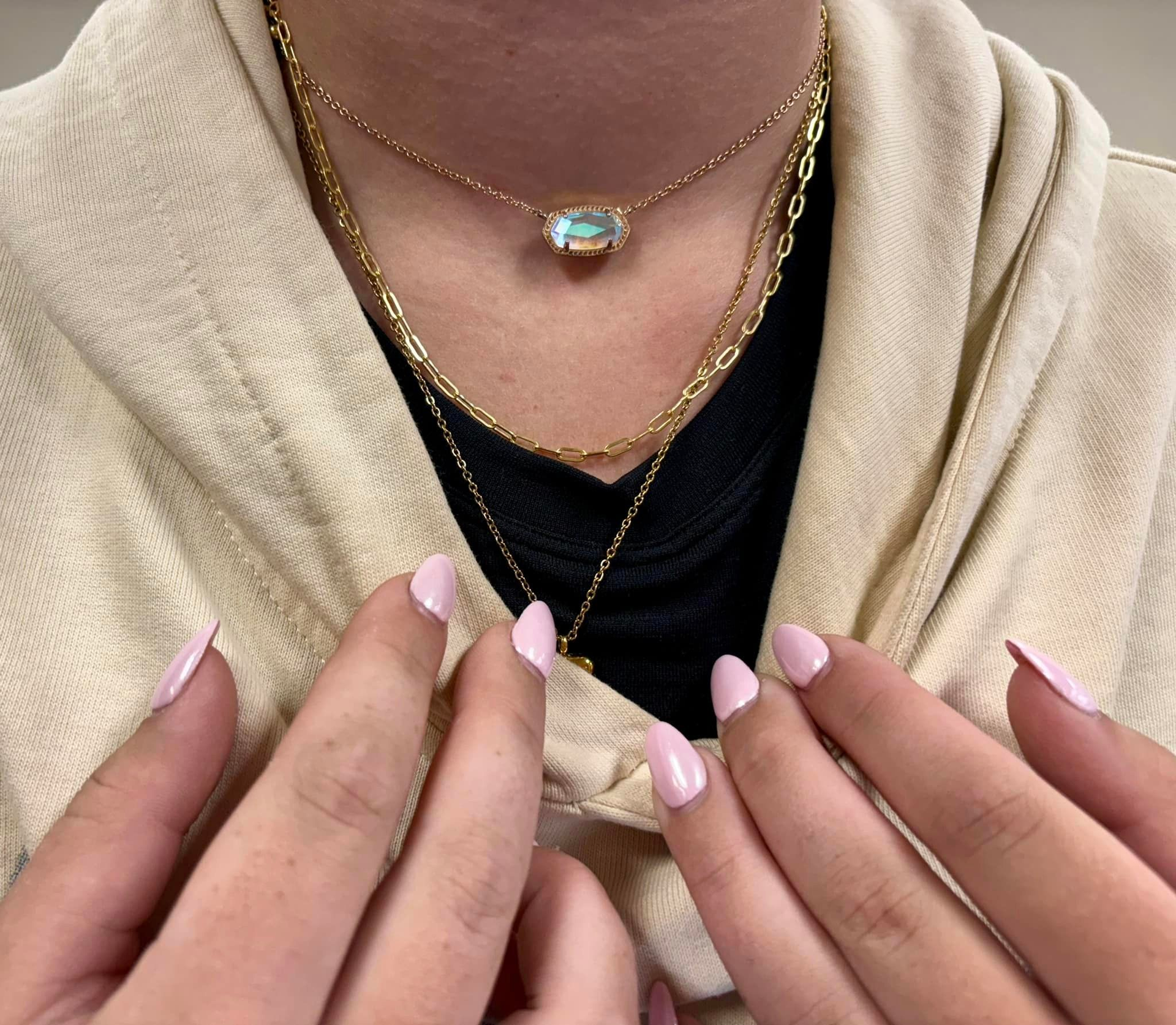 A woman wearing a plaid shirt and a necklace with a dragonfly pendant.