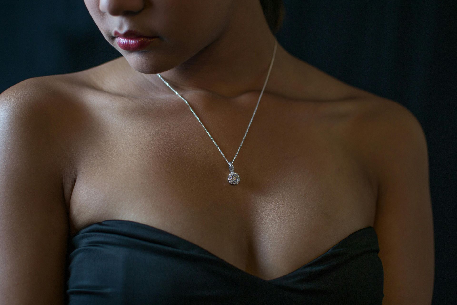 A woman wearing a black strapless top and a silver necklace