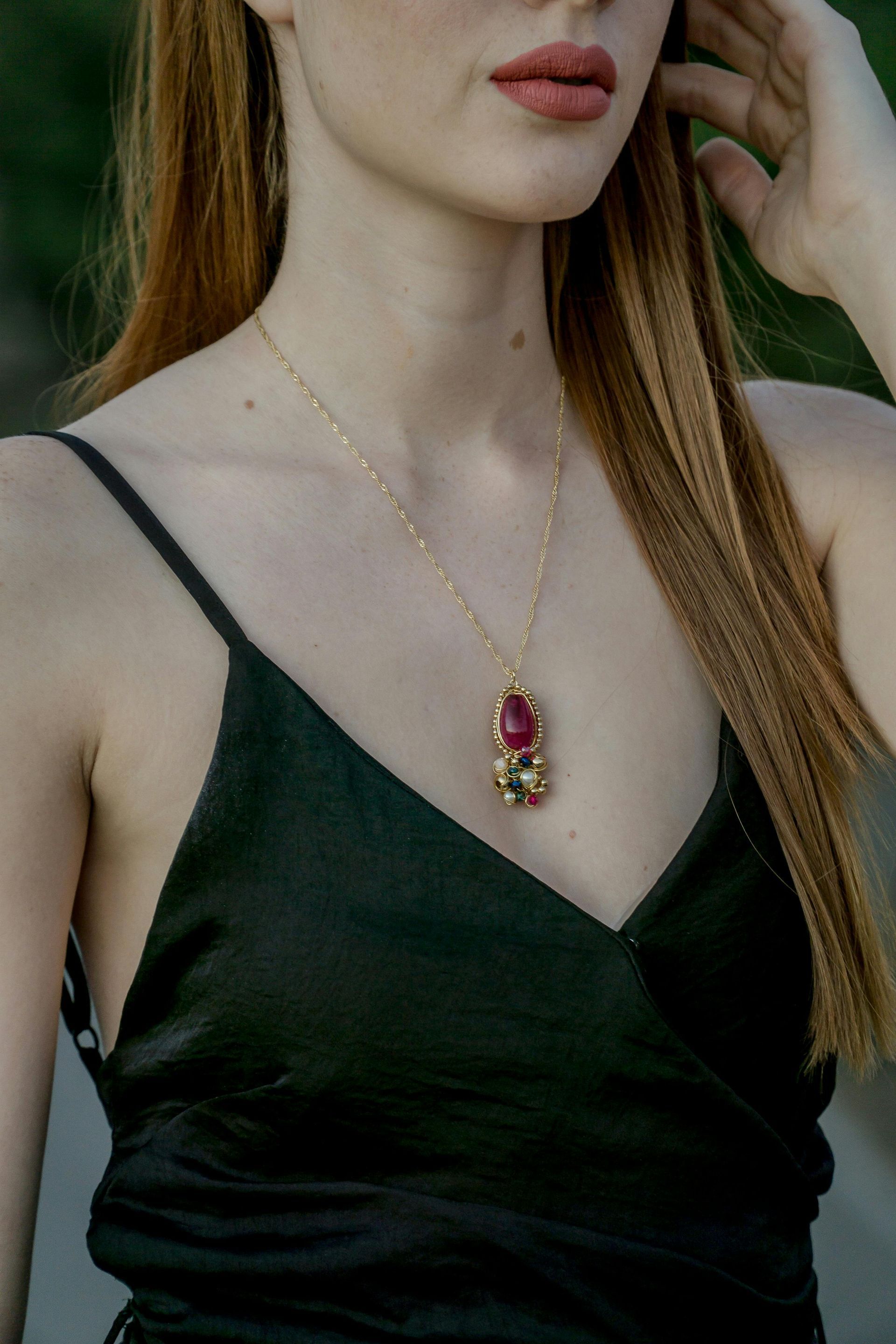 A woman is wearing a black tank top and a necklace.