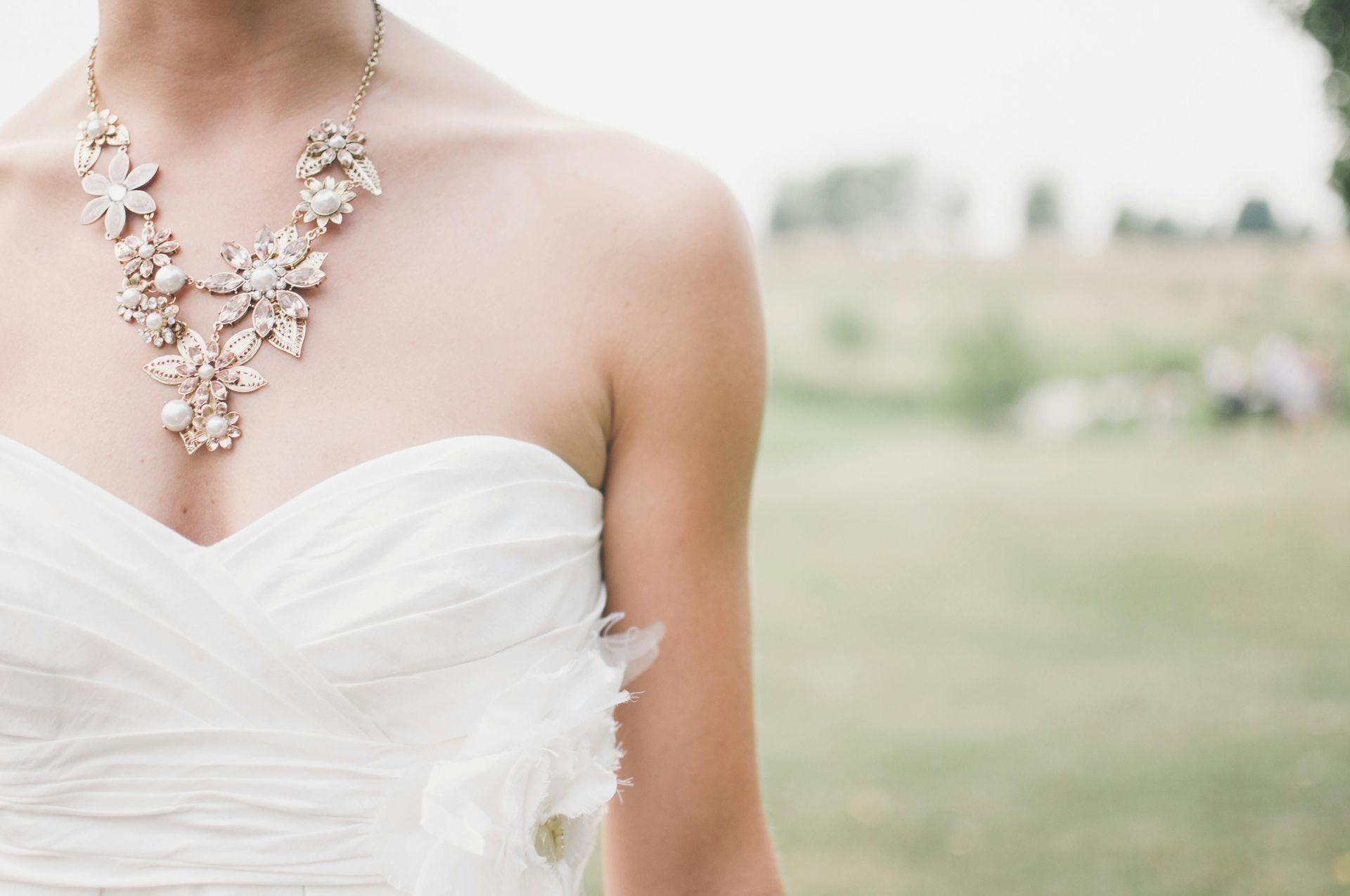 A woman in a wedding dress is wearing a necklace.