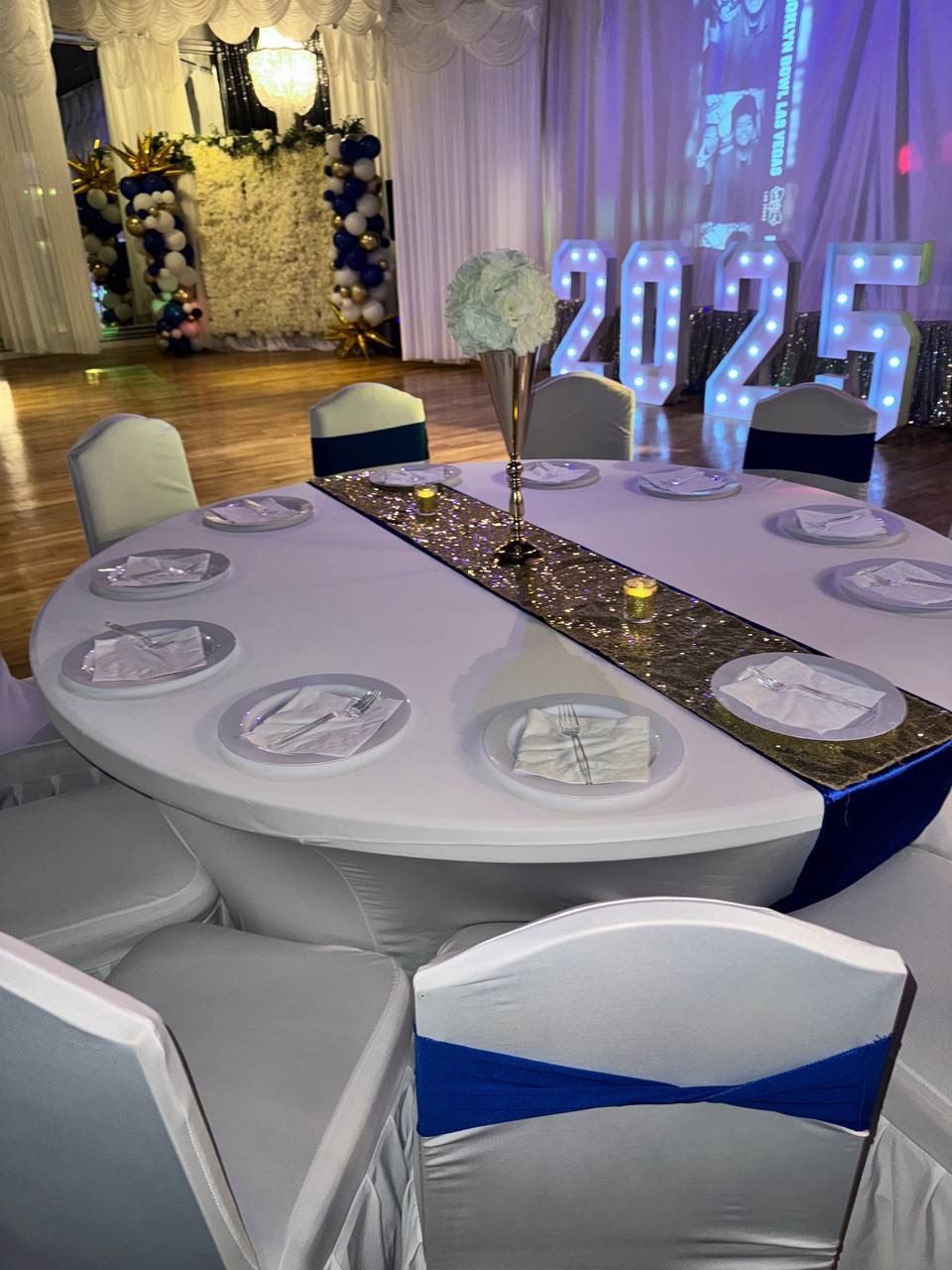 Formal event space with round tables set for dining, decorated with red and gold accents.