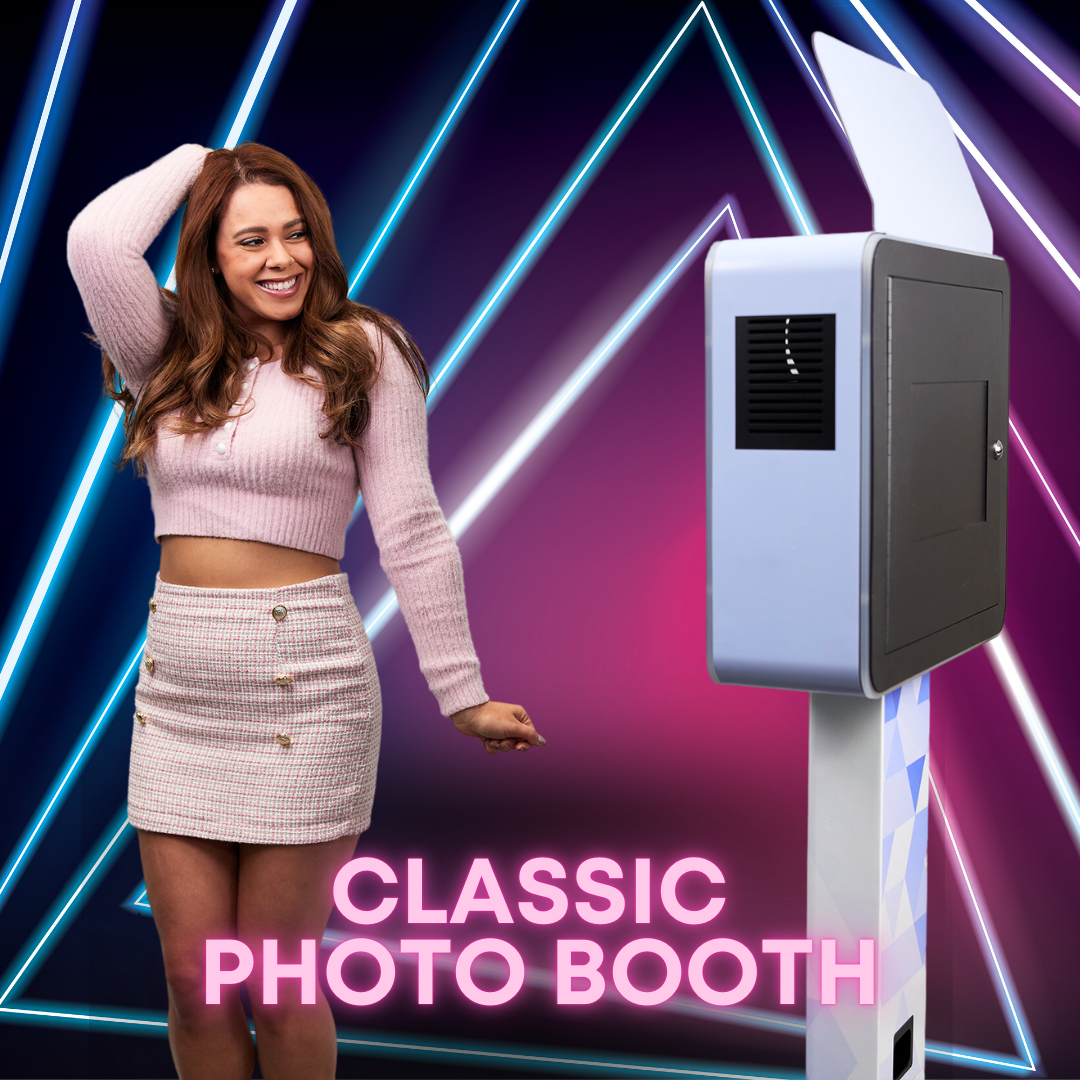 Woman poses next to a classic photo booth against a neon-light background.