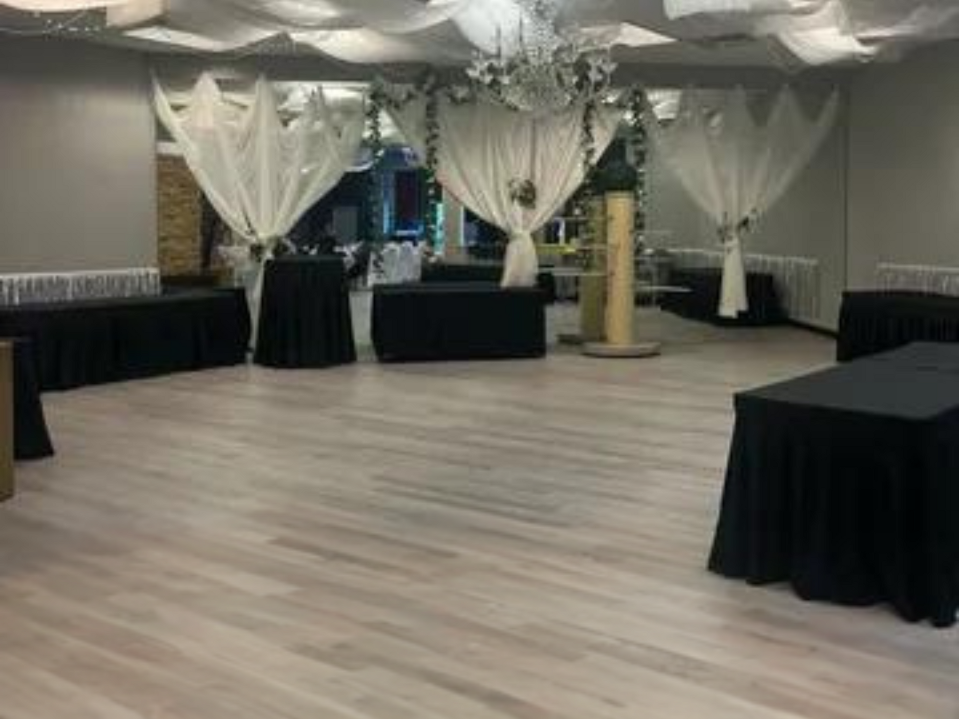 A large room with tables and curtains and a chandelier.