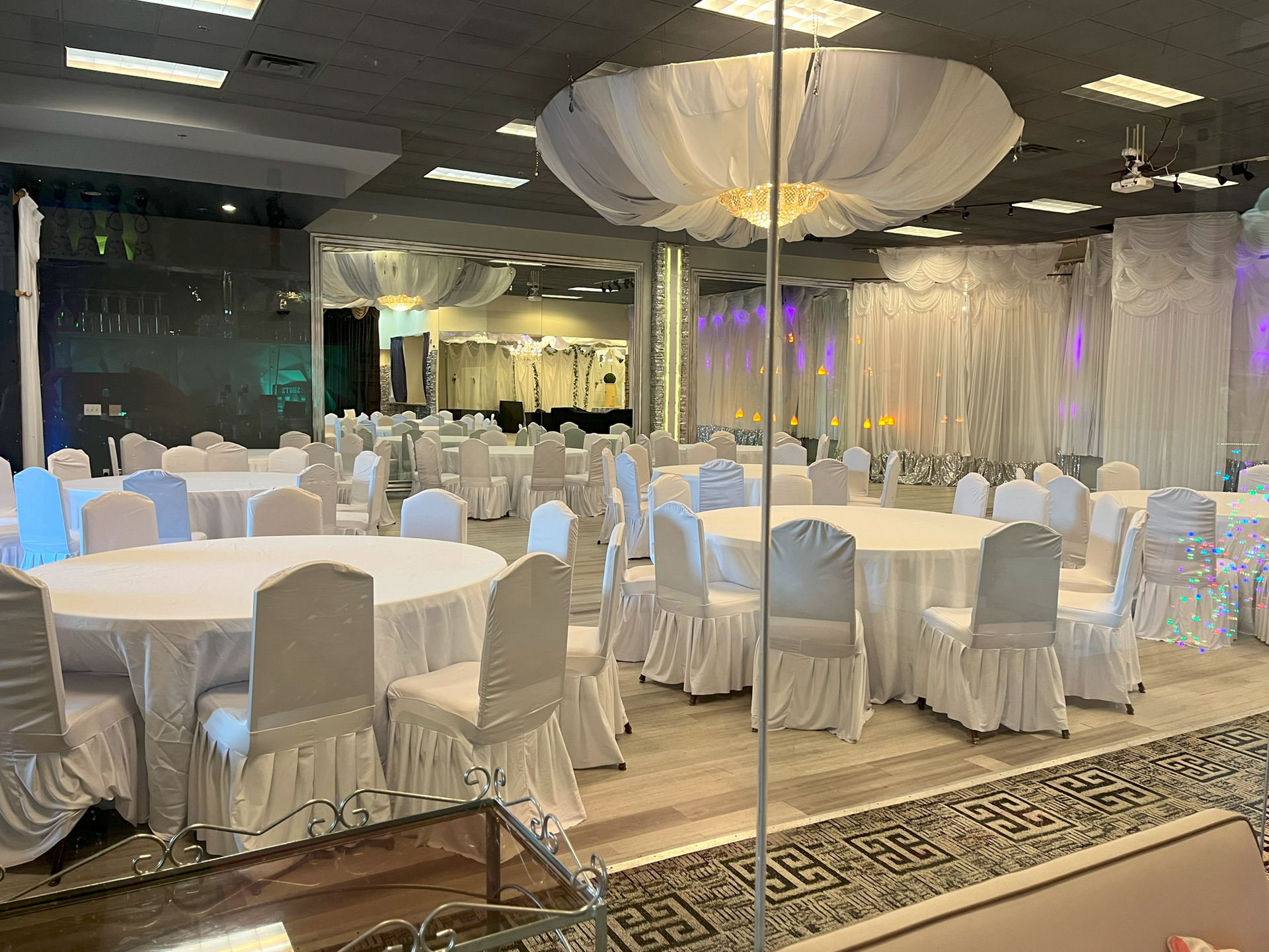 A large room with tables and chairs set up for a wedding reception.