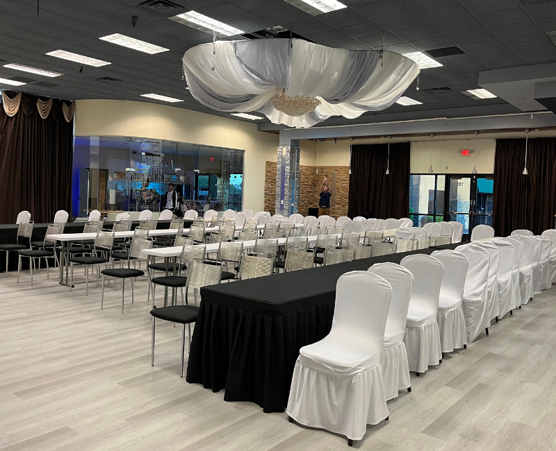 A large room with tables and chairs set up for a wedding reception.