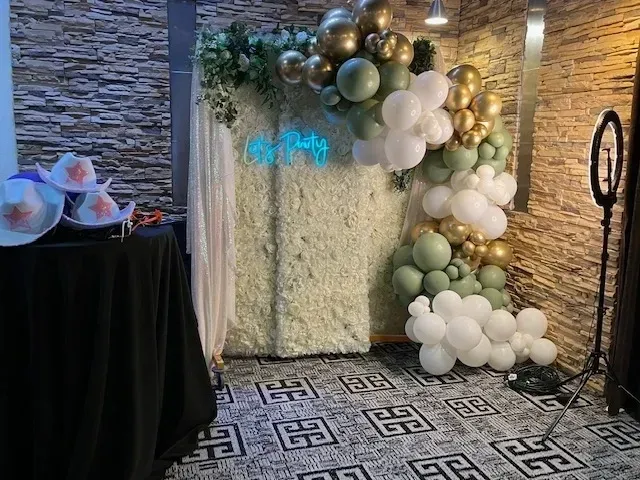 A room filled with balloons and a flower wall.