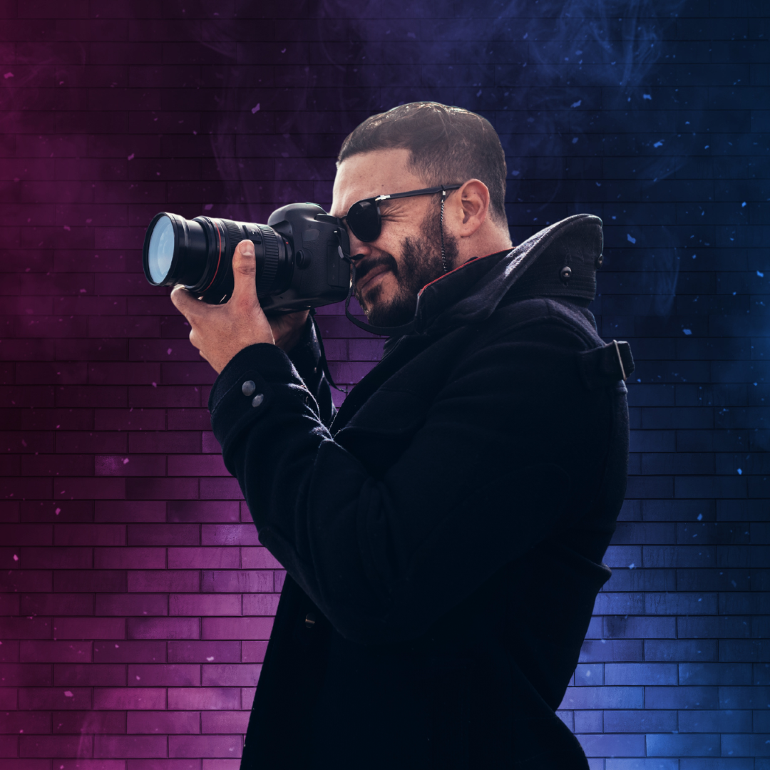A man taking a picture with a camera in front of a brick wall