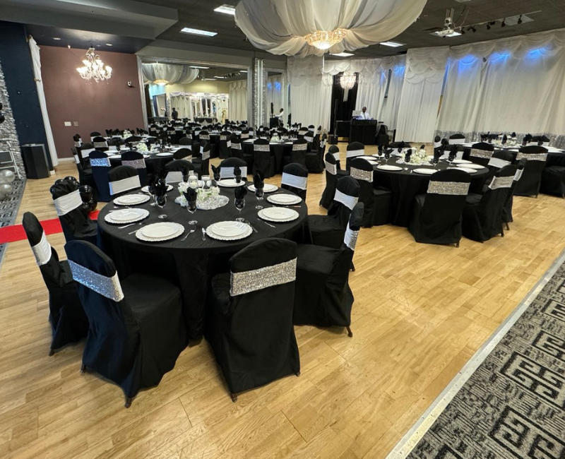 A large room with tables and chairs set up for a wedding reception.