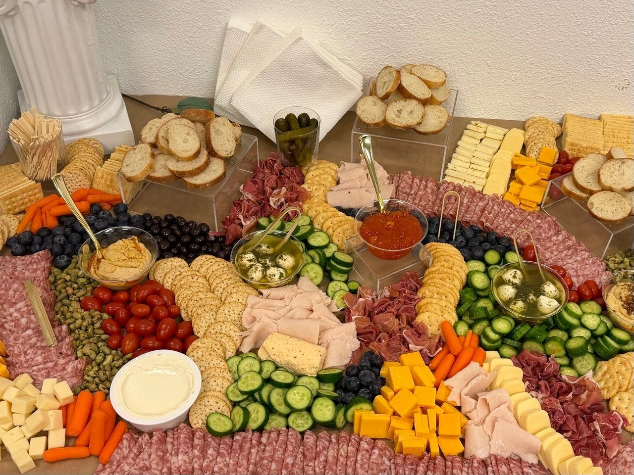 Colorful appetizer buffet with cheeses, crackers, cucumbers, grapes, carrots, and dips on a table