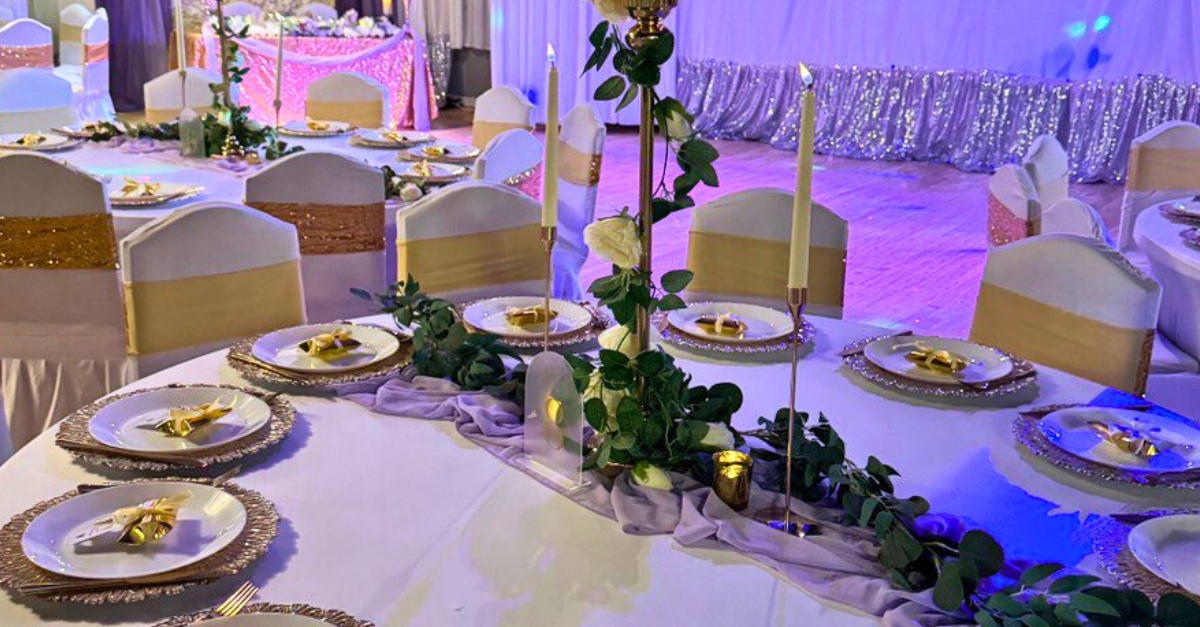 A long table with plates and candles on it is set up for a wedding reception.