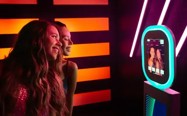 Two women are taking a picture of themselves in a photo booth.