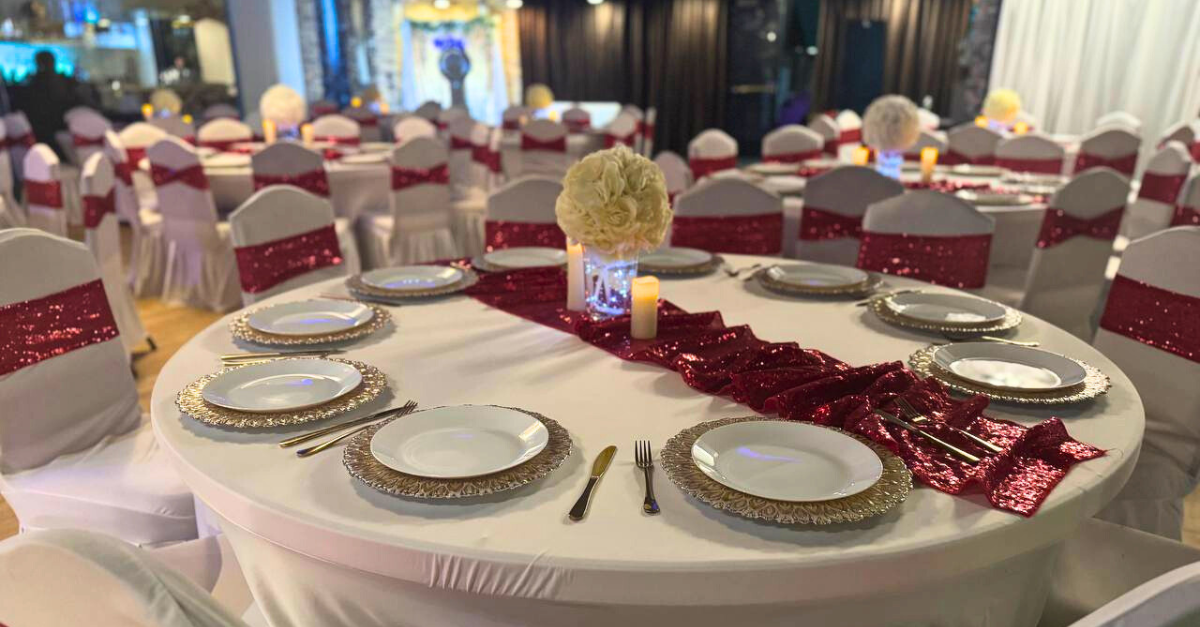 A table set for a wedding reception with plates , silverware , and candles.