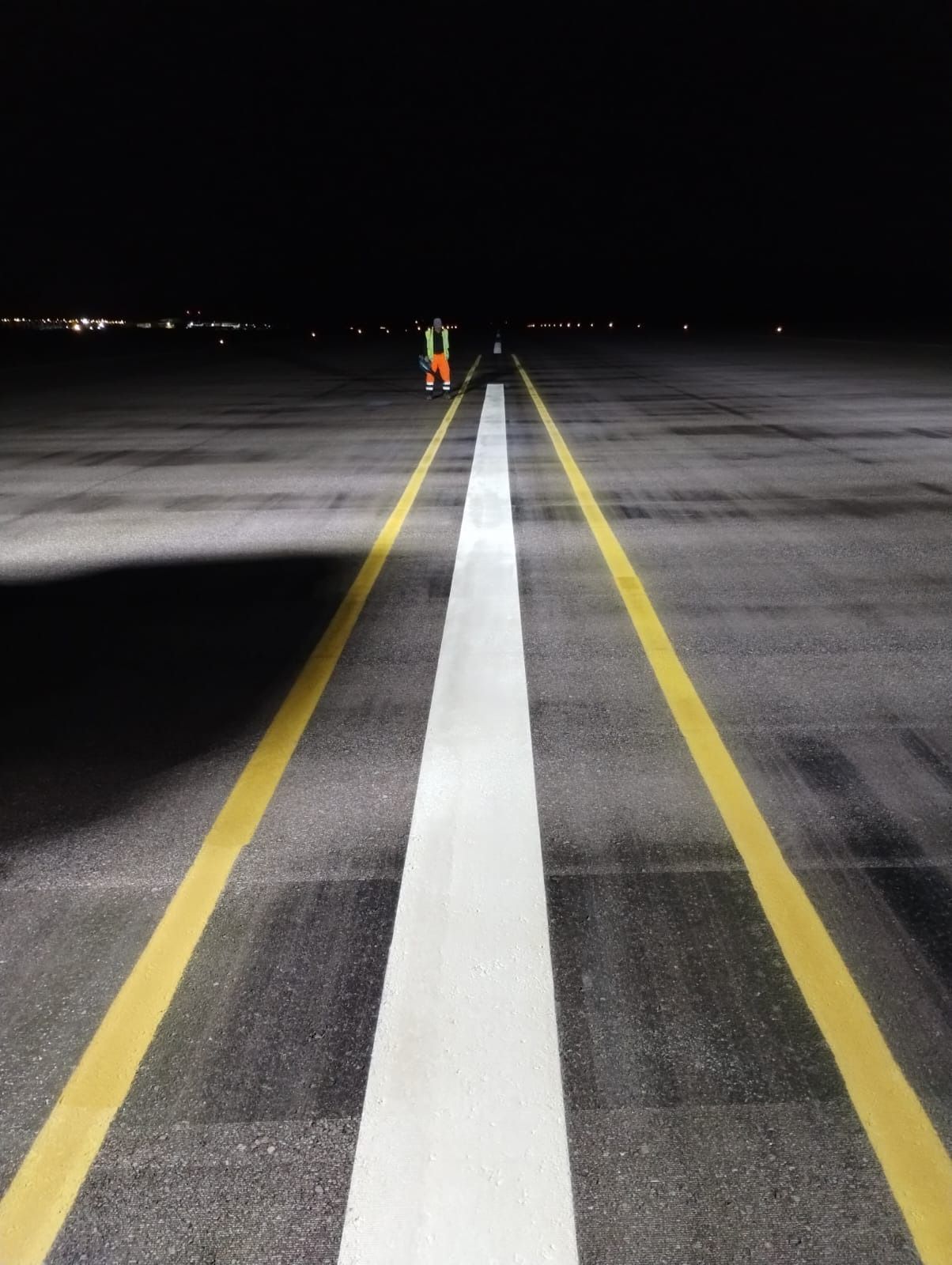 Una pista con líneas blancas y líneas amarillas por la noche