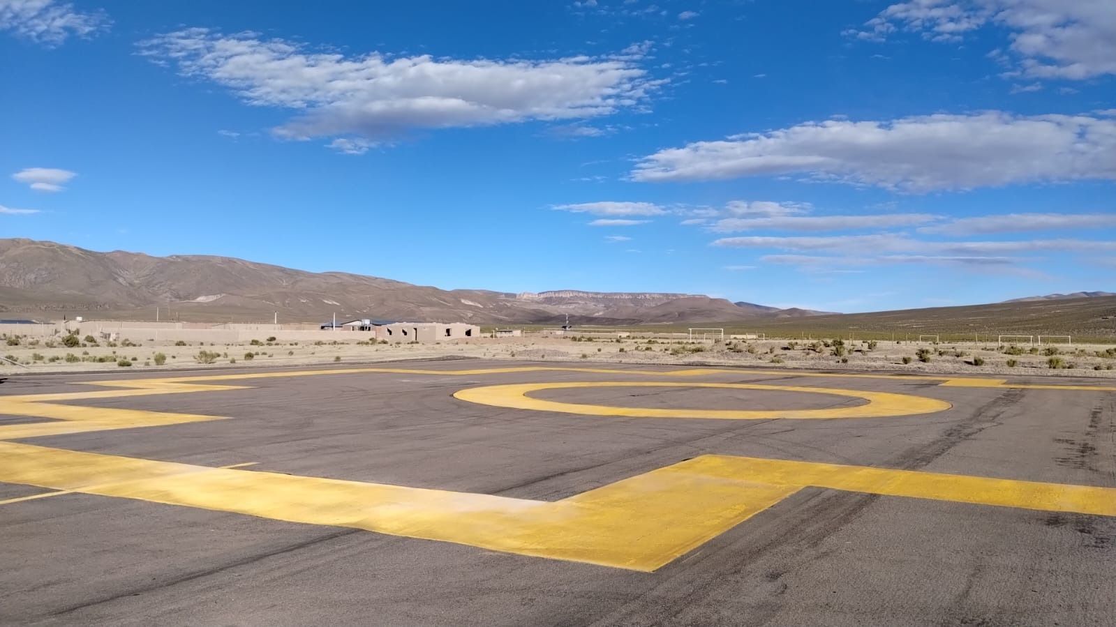 Una plataforma de aterrizaje para helicópteros con montañas al fondo.