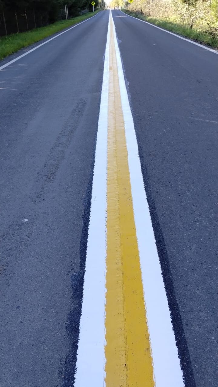 Una línea amarilla y blanca al costado de una carretera.