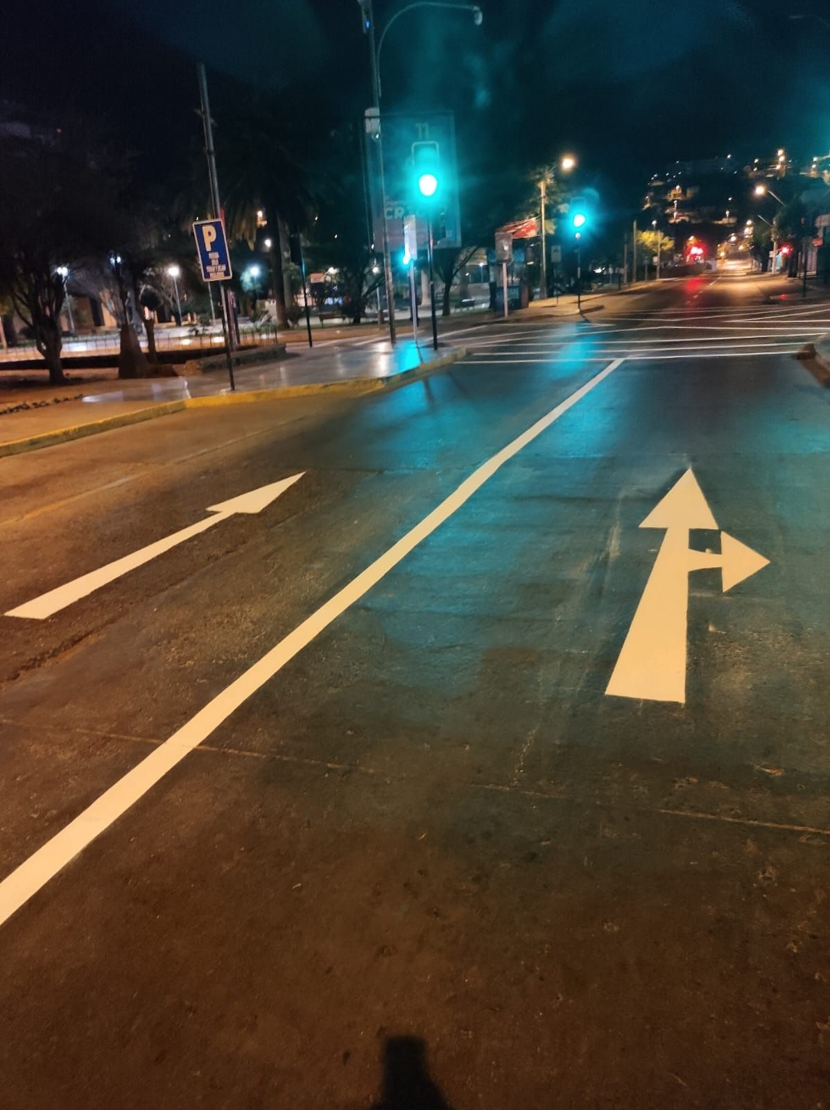 Una calle con una flecha blanca apuntando hacia la derecha