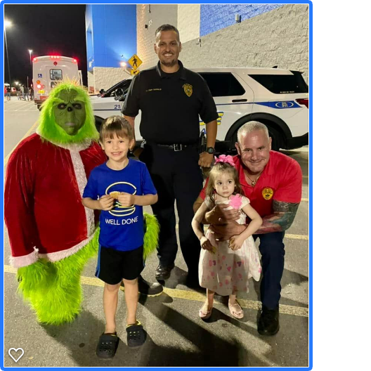 Grinch with children, police officer, and man in front of a police car. The Grinch smiles.