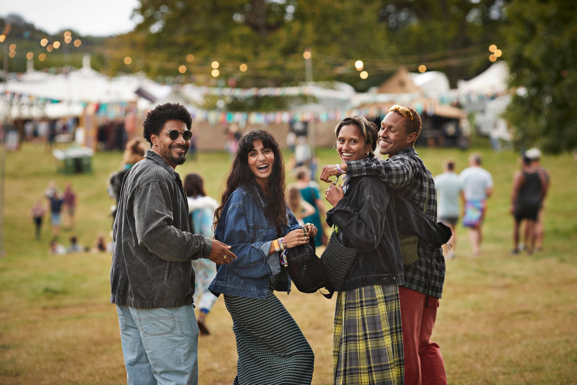 Four people smiling, posing together at an outdoor festival.