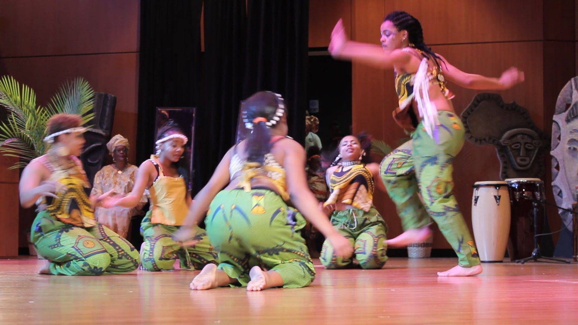 African dancers in colorful outfits on stage, performing.