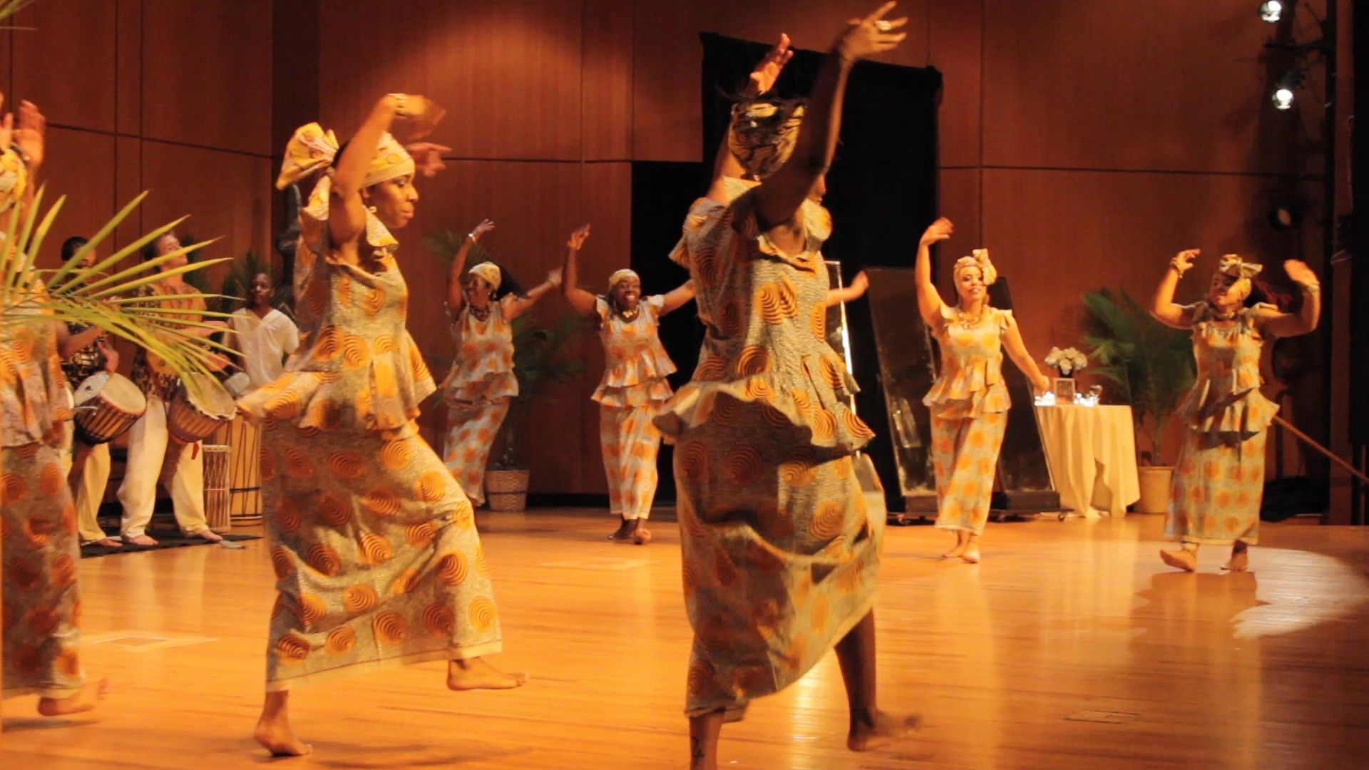 Dancers in yellow and white costumes perform on stage.