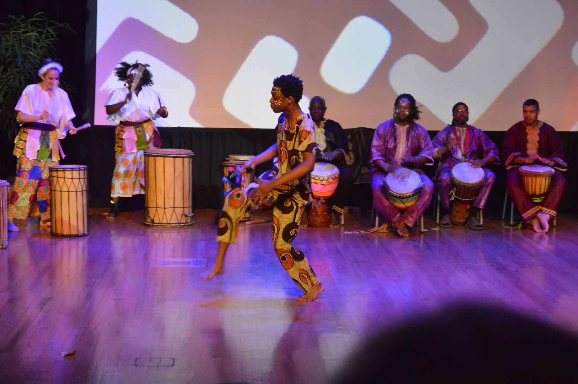 African dancers and drummers on stage with colorful clothing and drums.