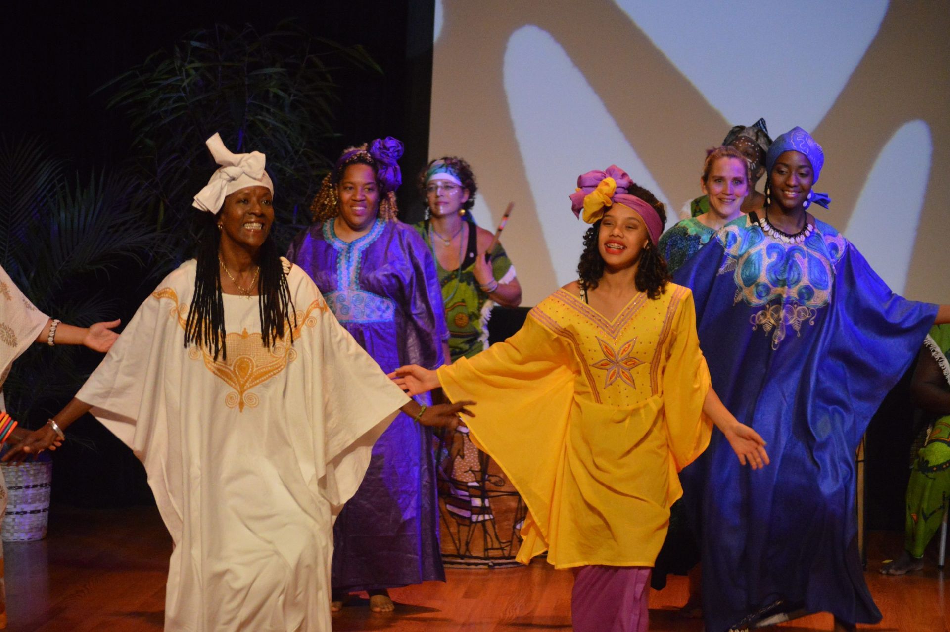 Group of women in colorful African garb dancing on stage.