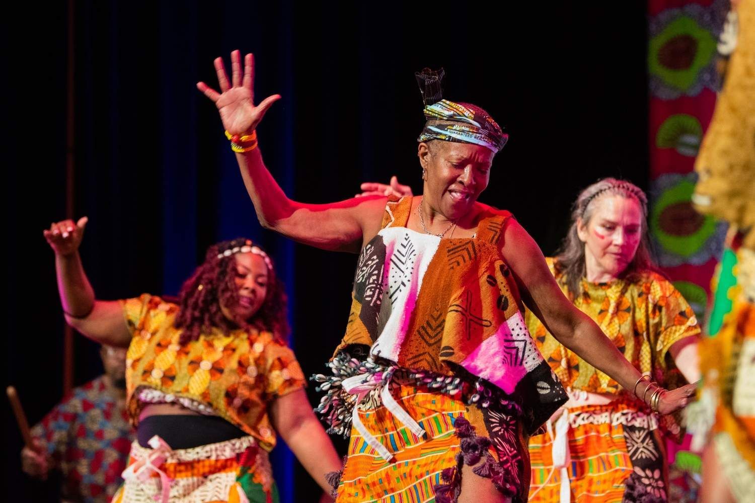 People dancing onstage in colorful African attire.