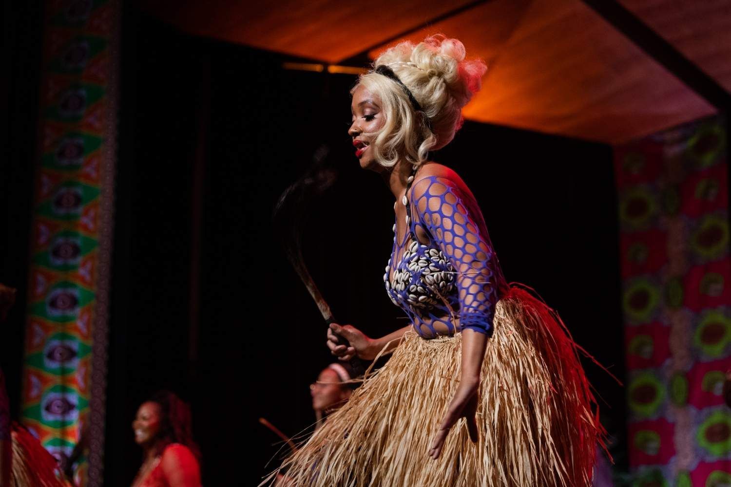 Woman in a costume sings and holds a blade during a performance.