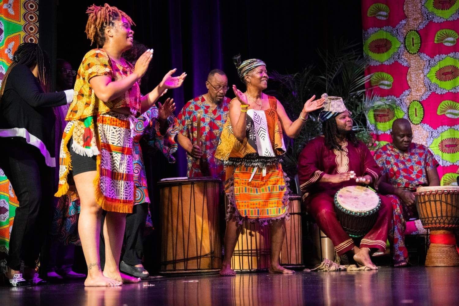 African dancers and drummers on stage, vibrant colors, performing.