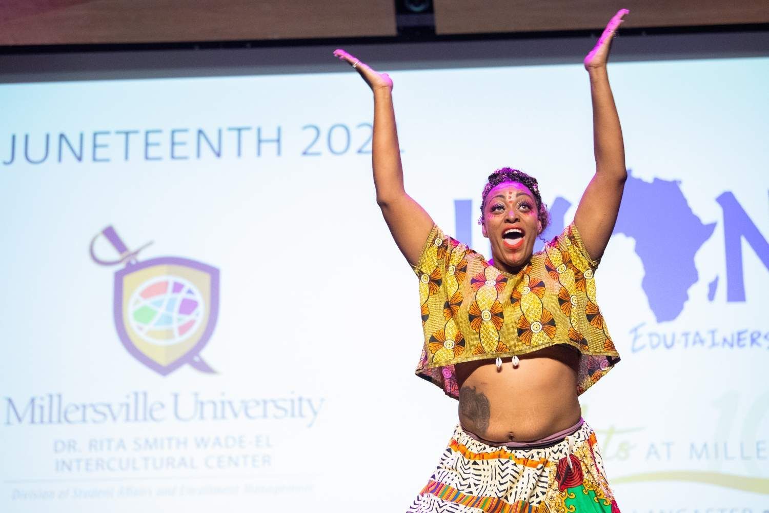 Woman in yellow top with arms up, celebrating Juneteenth at Millersville University.