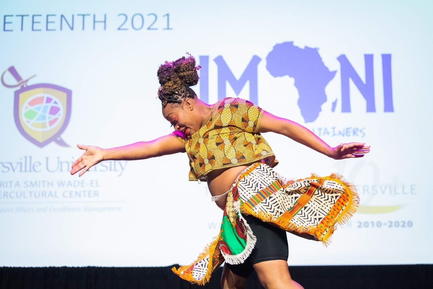 A dancer in African print costume performs on stage at Juneteenth celebration.